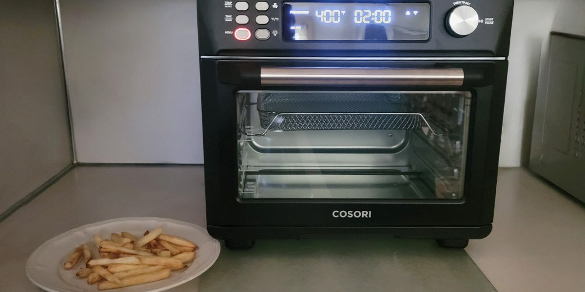 Cosori Smart Air Fryer Toaster Oven on counter with plate of fries in front Cosori Smart Air Fryer Toaster Oven on counter with plate of fries in front