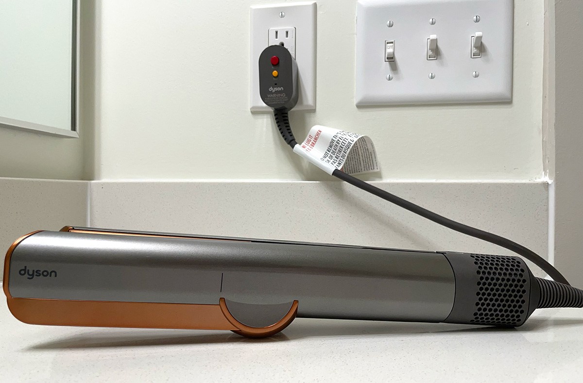 A dyson hair straightener plugged in a wall outlet 