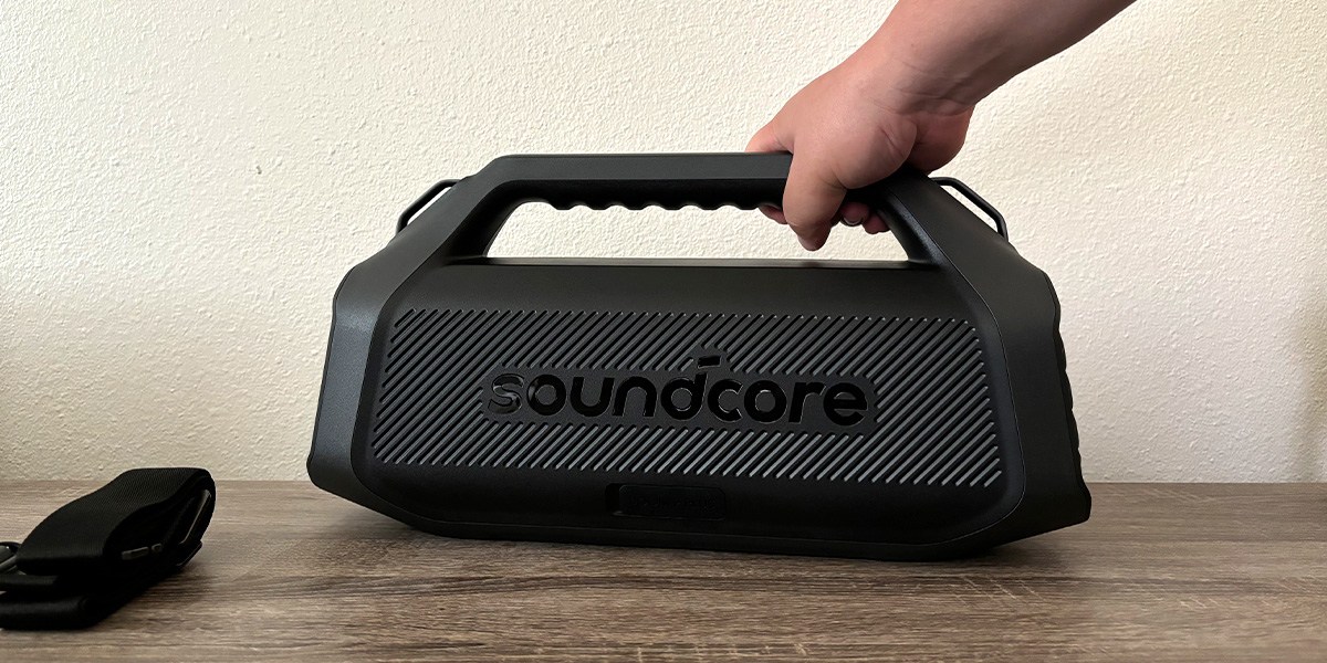 Soundcore Boom 2 Plus Outdoor on table with hand clutching handle