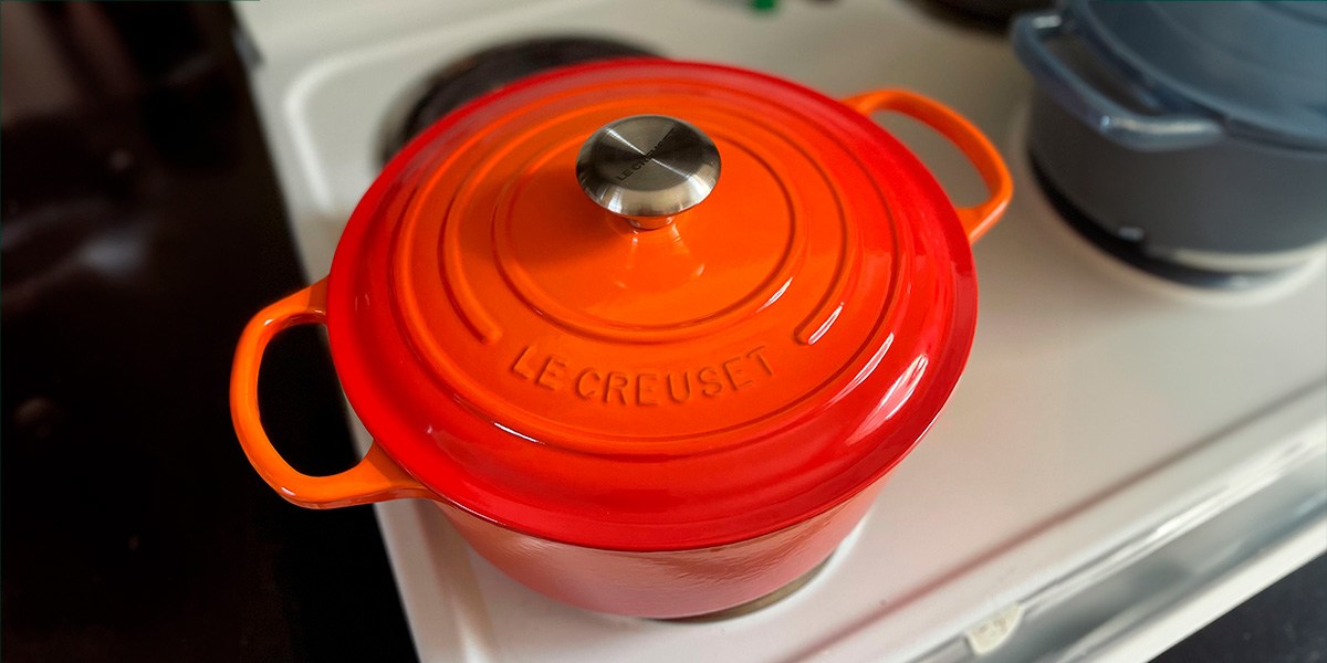 Top view of orange Le Creuset Round Dutch Oven on stovetop burner Top view of orange Le Creuset Round Dutch Oven on stovetop burner