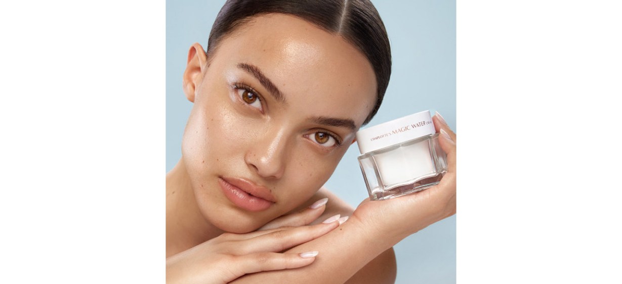 Woman holding jar of Charlotte Tilbury Magic Water Cream next to her face