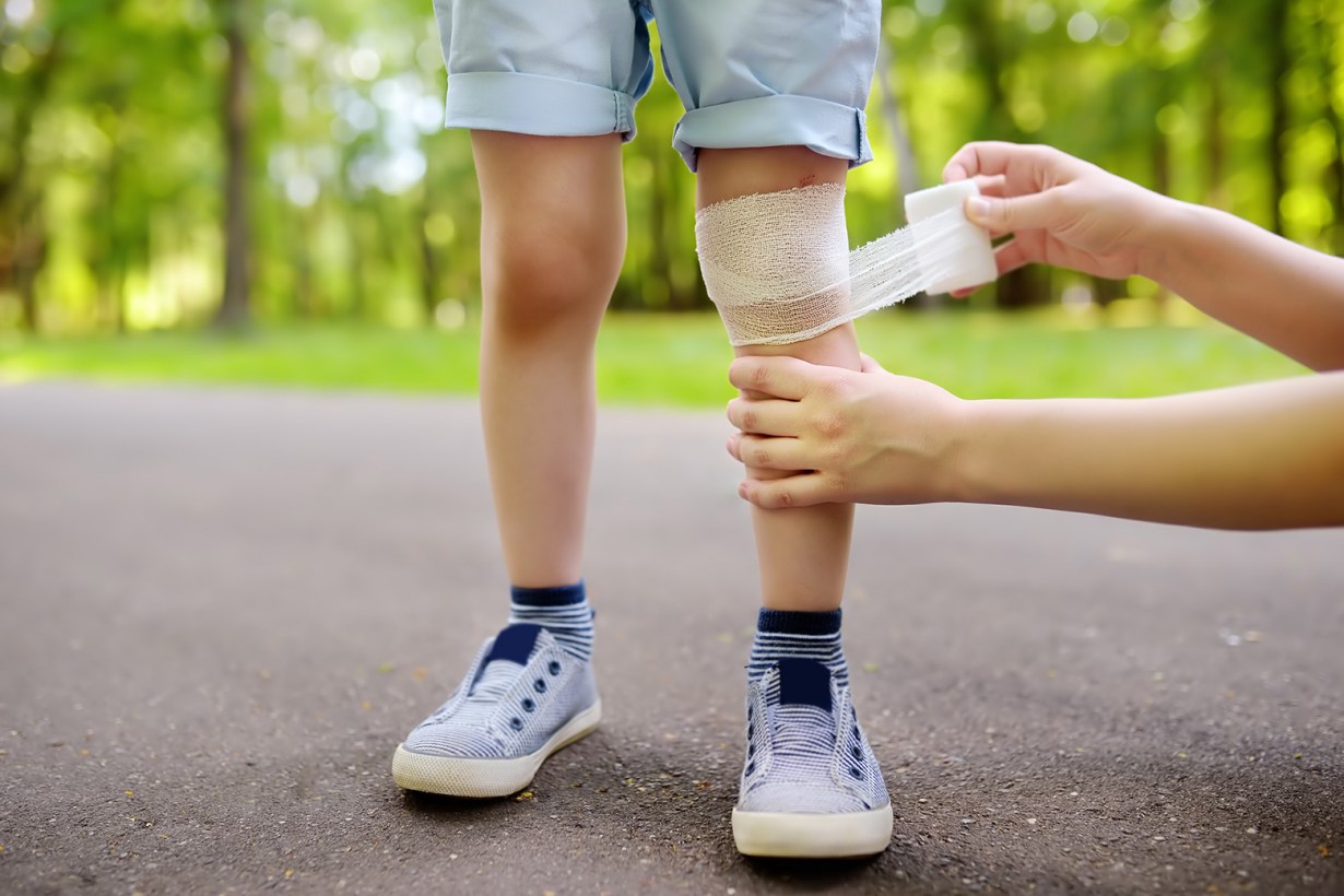 a person wrapping gauze on a kid's knee