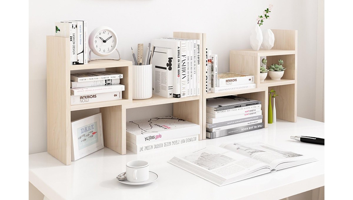 A beige Jerry and Maggie Desktop Office Organizer on a desk behind a cup and saucer, an open book and a pen.