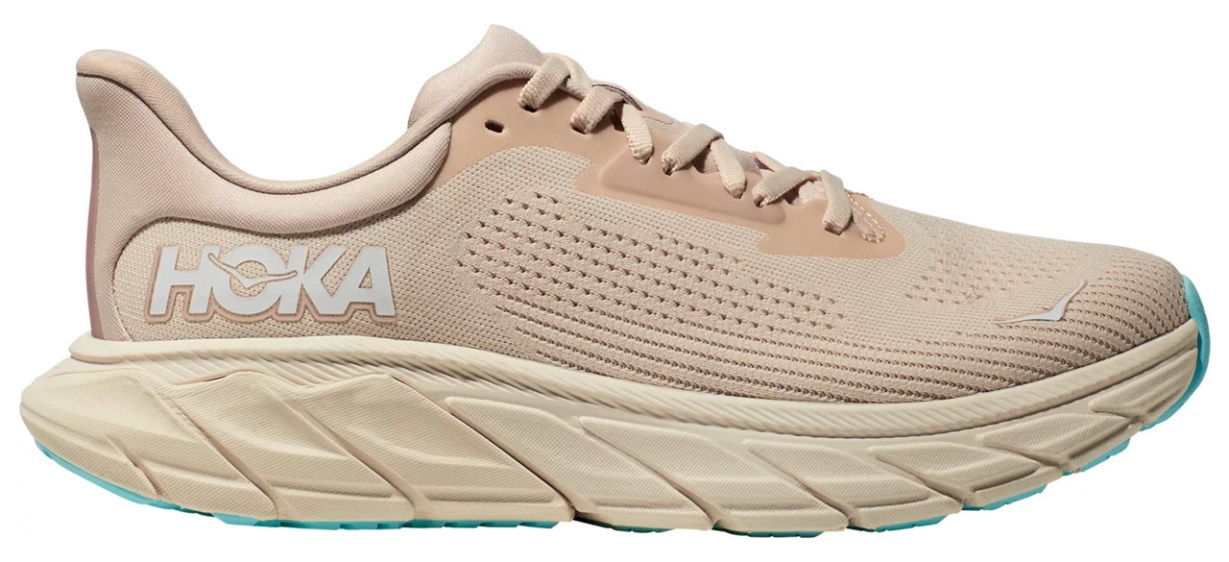 A beige Hoka sneaker with light pink and tan accents.