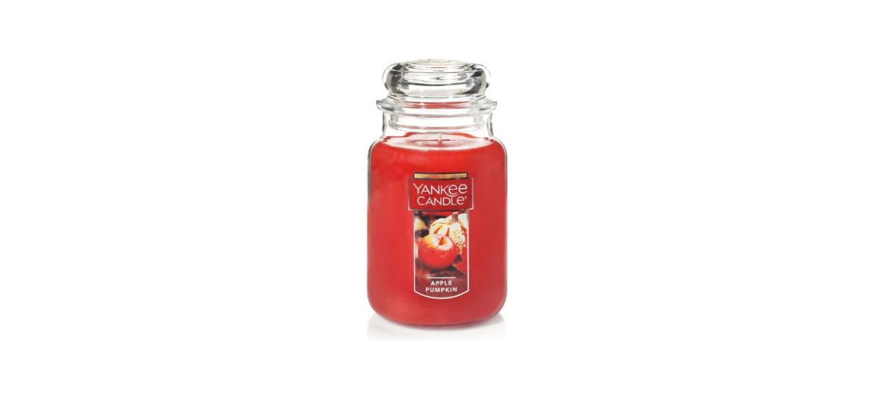 A large red candle in a glass jar with a label that says &quot;apple pumpkin&quot; on it and has a picture of an apple and a pumpkin.